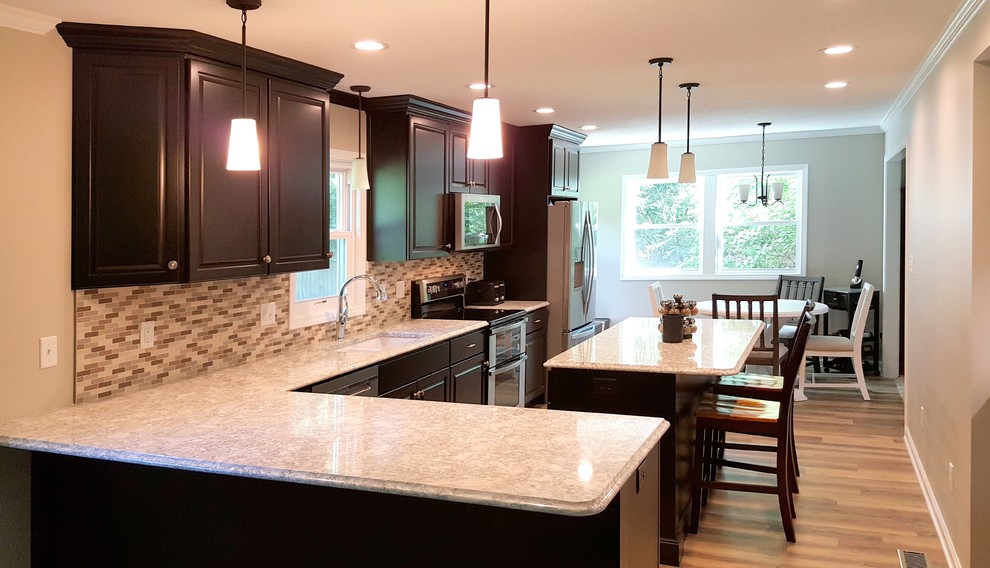 Large transitional l-shaped medium tone wood floor and brown floor eat-in kitchen photo with an undermount sink, raised-panel cabinets, quartz countertops, multicolored backsplash, ceramic backsplash, stainless steel appliances and an island