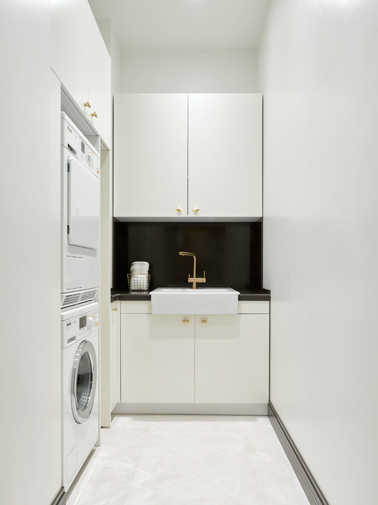 Transitional dedicated laundry room in Moscow with flat-panel cabinets, white cabinets, white walls, a stacked washer and dryer, white floor, an utility sink, porcelain floors and brown benchtop.