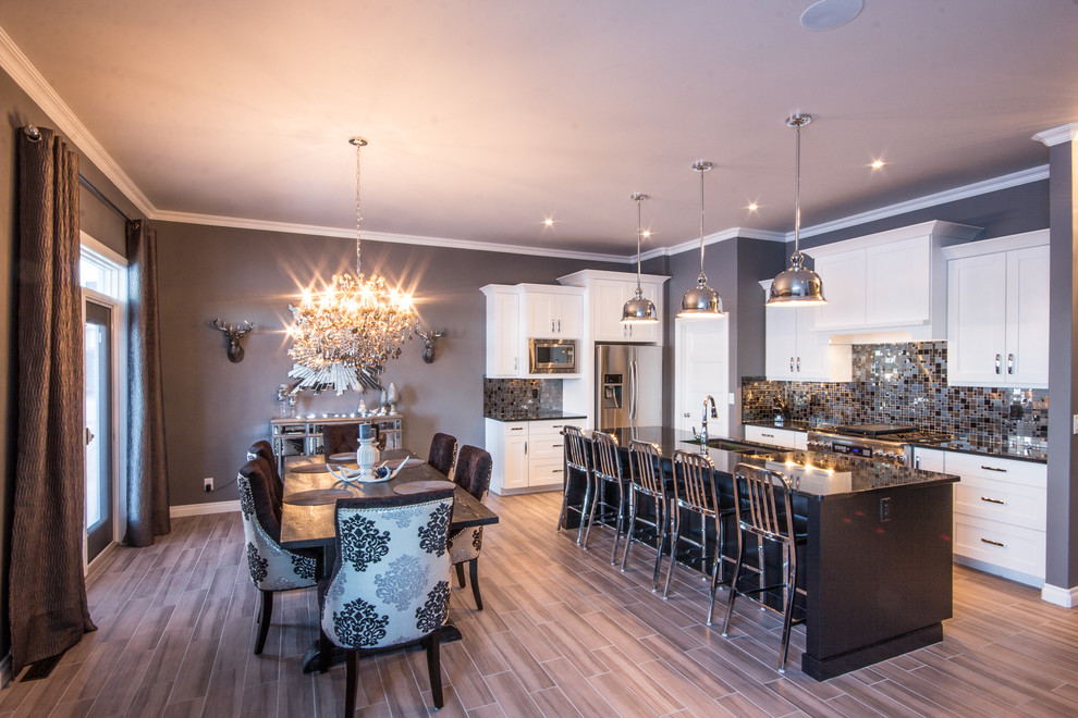 Example of a mid-sized transitional l-shaped porcelain tile eat-in kitchen design in Calgary with a double-bowl sink, shaker cabinets, white cabinets, multicolored backsplash, mosaic tile backsplash, stainless steel appliances, an island and quartz countertops