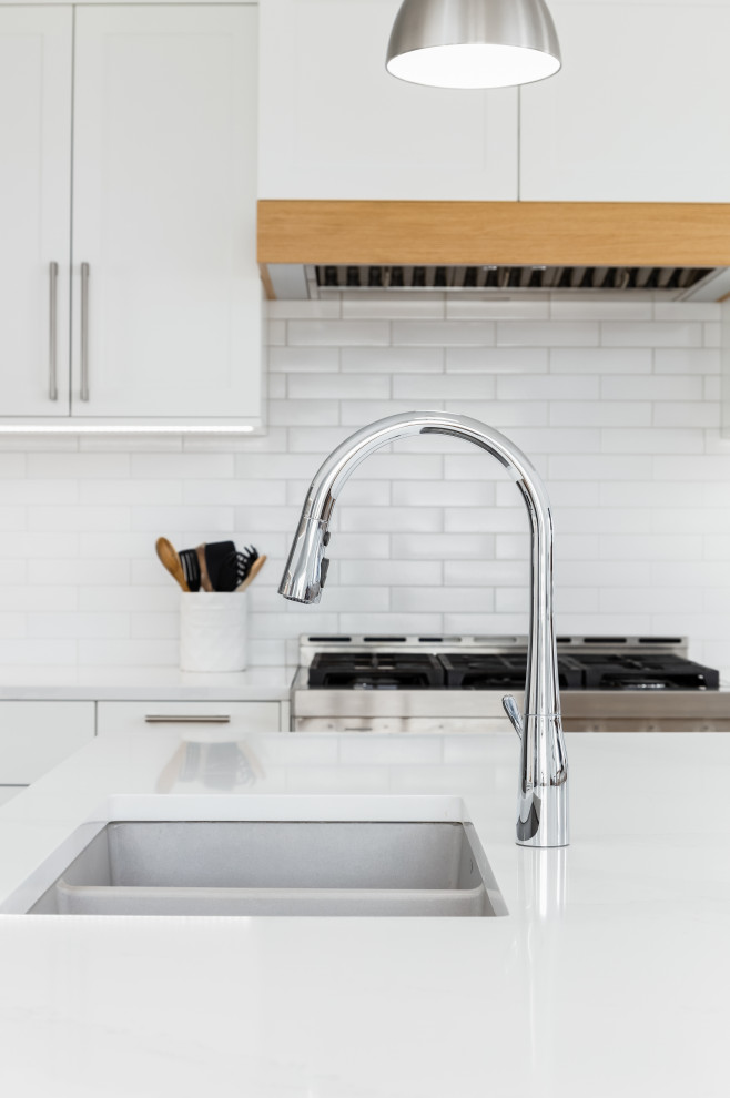 Mid-sized transitional l-shaped light wood floor and beige floor eat-in kitchen photo in Vancouver with an undermount sink, shaker cabinets, white cabinets, quartzite countertops, white backsplash, subway tile backsplash, stainless steel appliances, an island and white countertops