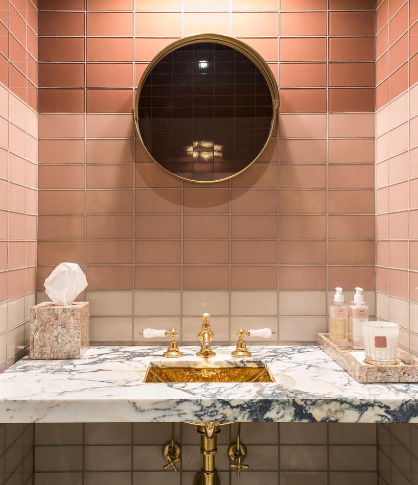 This is an example of a small traditional powder room in Other with pink tile, pink walls, marble benchtops and multi-coloured benchtops.