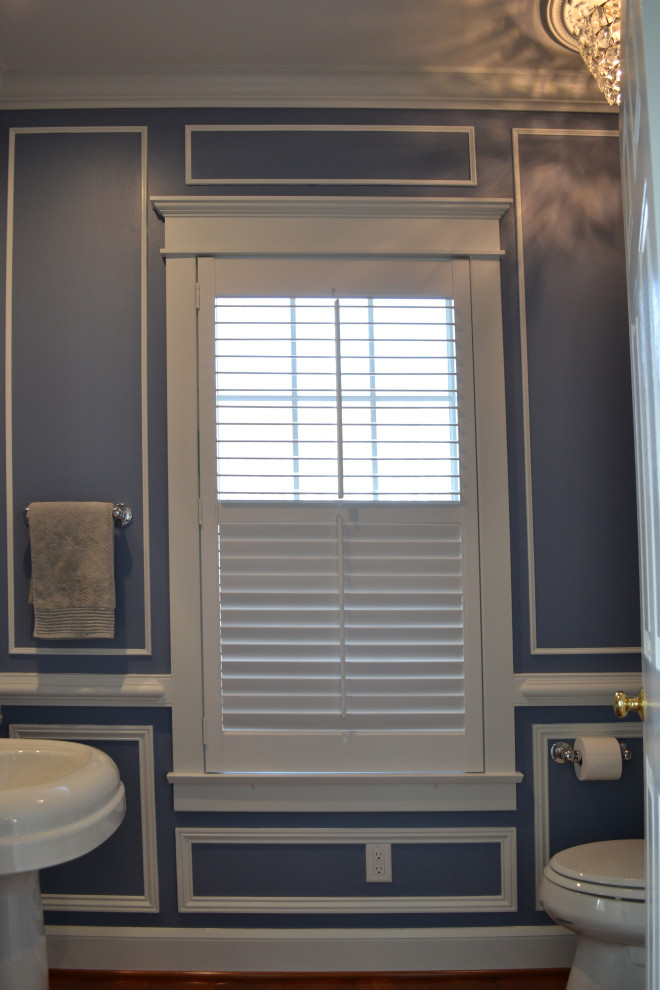 This is an example of a mid-sized traditional powder room in Other with blue walls and light hardwood floors.