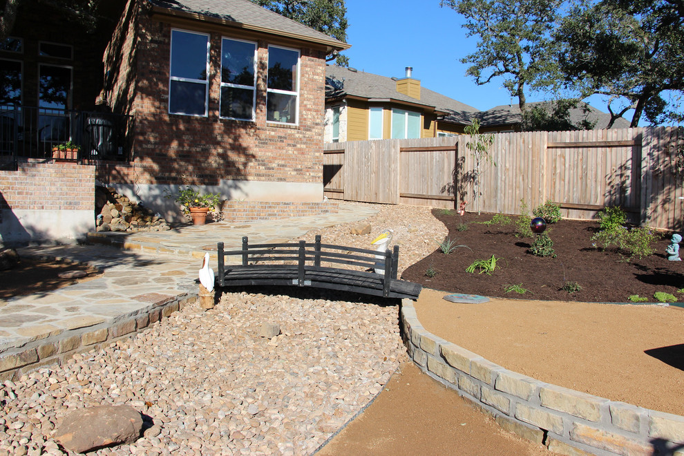 This is an example of a mid-sized rustic full sun and drought-tolerant backyard stone landscaping in Austin for summer.