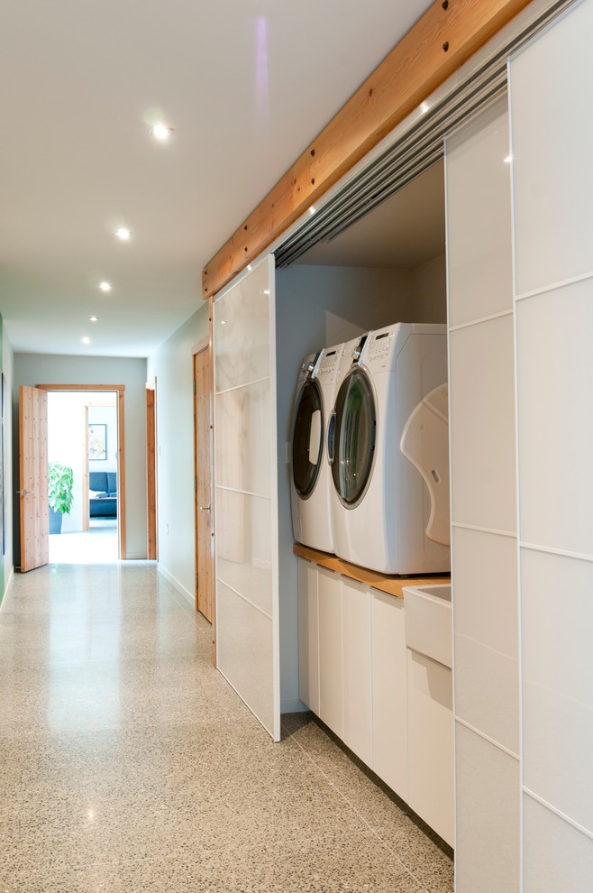 This is an example of a large contemporary laundry cupboard in Vancouver with grey walls and concrete floors.