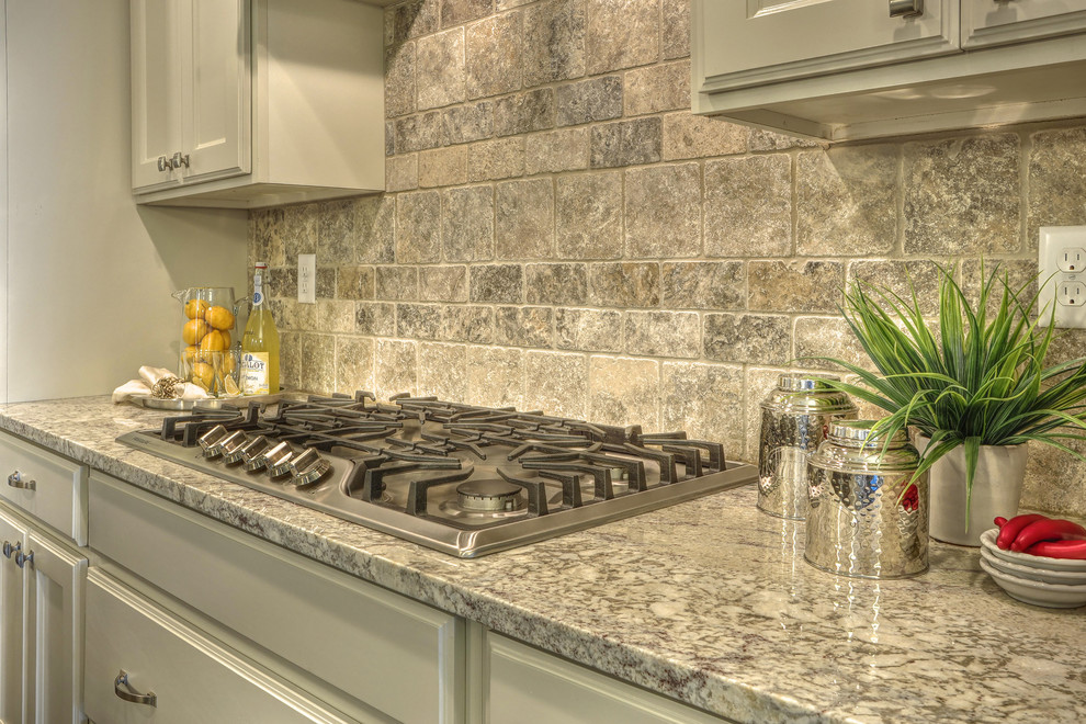 Example of a small transitional l-shaped medium tone wood floor eat-in kitchen design in Boise with an undermount sink, recessed-panel cabinets, white cabinets, granite countertops, beige backsplash, stone tile backsplash, stainless steel appliances and an island