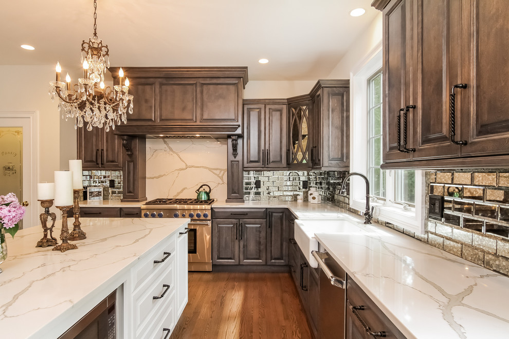 Mid-sized traditional u-shaped kitchen in Other with a farmhouse sink, raised-panel cabinets, marble benchtops, metallic splashback, subway tile splashback, stainless steel appliances, medium hardwood floors, with island and grey cabinets.