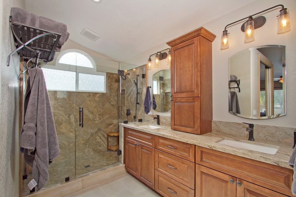 Design ideas for a large traditional master bathroom in San Diego with recessed-panel cabinets, medium wood cabinets, a corner shower, a two-piece toilet, beige tile, travertine, yellow walls, porcelain floors, beige floor, a hinged shower door, an undermount sink, engineered quartz benchtops, beige benchtops, a double vanity and a built-in vanity.