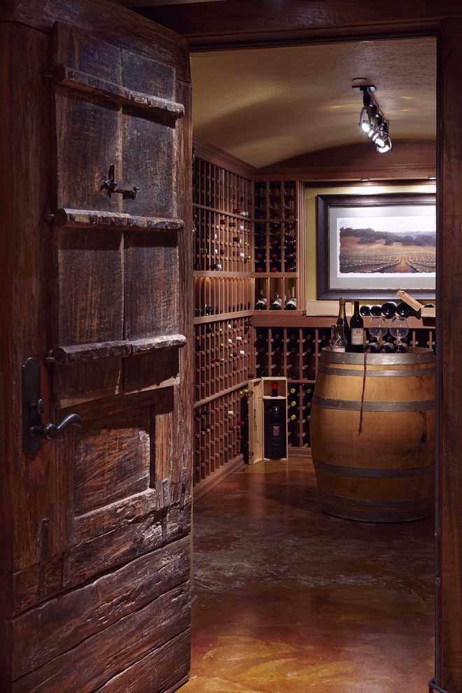 Large traditional wine cellar in Seattle with concrete floors, storage racks and orange floor.