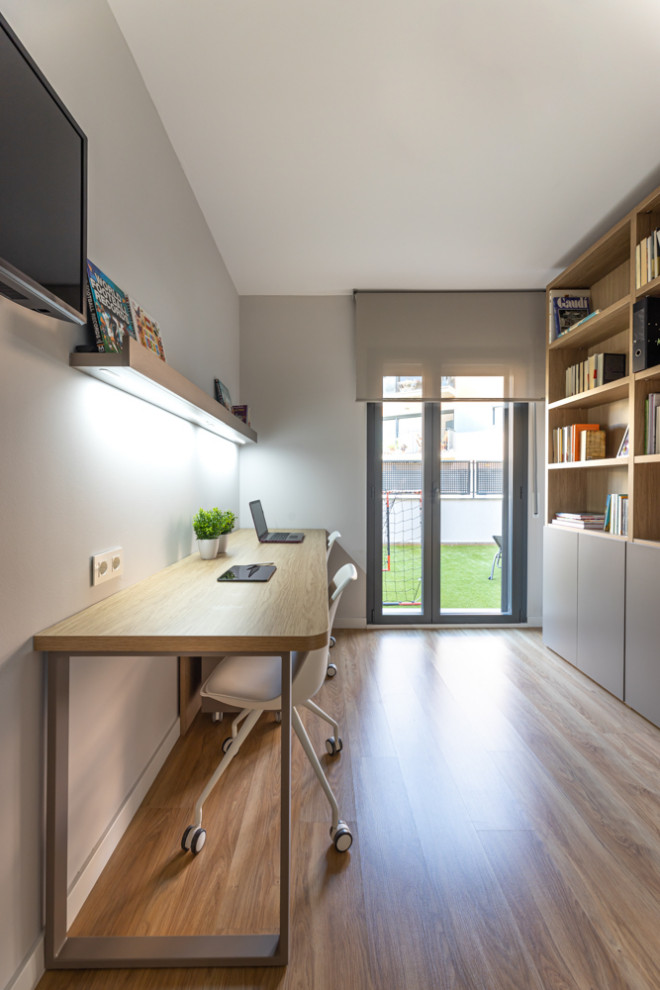 Small scandinavian study in Barcelona with grey walls, medium hardwood flooring, a freestanding desk and brown floors.