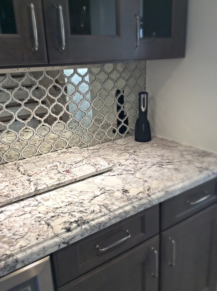 Example of a mid-sized transitional u-shaped ceramic tile eat-in kitchen design in Houston with a farmhouse sink, recessed-panel cabinets, white cabinets, granite countertops, white backsplash, stone tile backsplash, stainless steel appliances and an island
