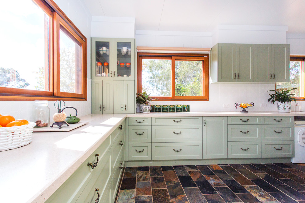 This is an example of a small country galley kitchen in Other with a double-bowl sink, shaker cabinets, green cabinets, solid surface benchtops, white splashback, metal splashback, slate floors, multi-coloured floor and beige benchtop.