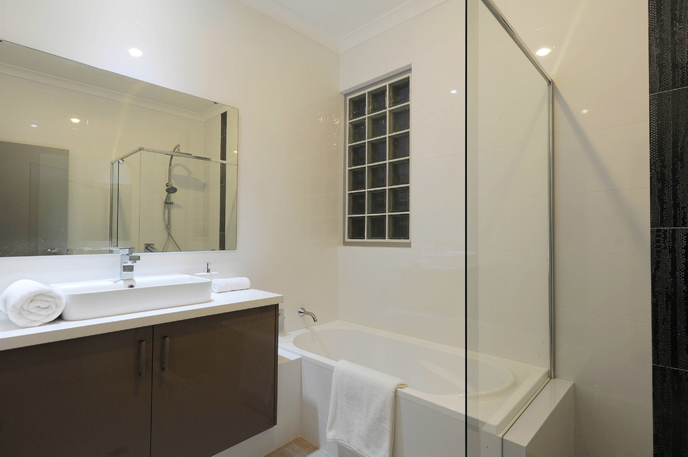 This is an example of a mid-sized contemporary master bathroom in Perth with flat-panel cabinets, grey cabinets, a corner tub, a corner shower, a one-piece toilet, white tile, white walls and a drop-in sink.
