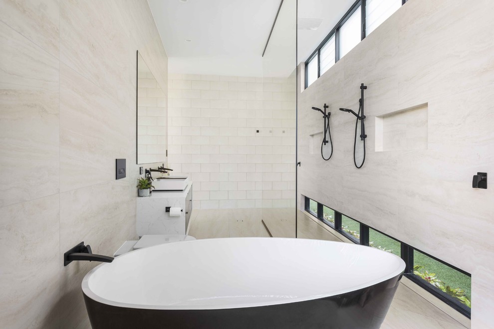 Design ideas for a contemporary master bathroom in Gold Coast - Tweed with black cabinets, a freestanding tub, an open shower, beige tile, ceramic tile, white walls, ceramic floors, a vessel sink, marble benchtops, beige floor, an open shower and white benchtops.