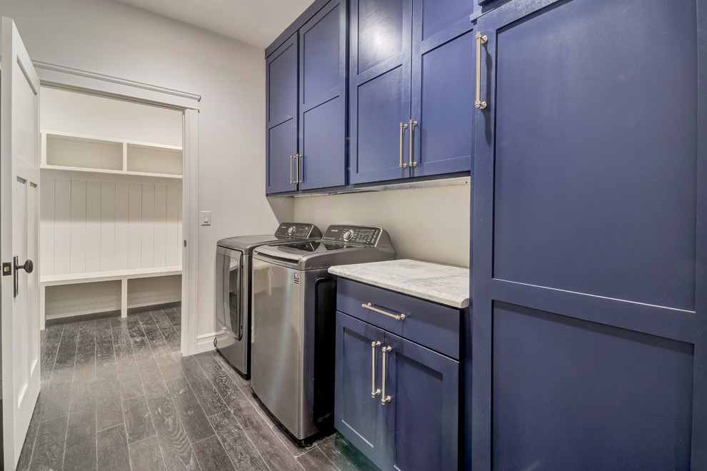 Design ideas for a large transitional single-wall dedicated laundry room in Salt Lake City with shaker cabinets, blue cabinets, marble benchtops, beige walls, dark hardwood floors, a side-by-side washer and dryer, brown floor and white benchtop.