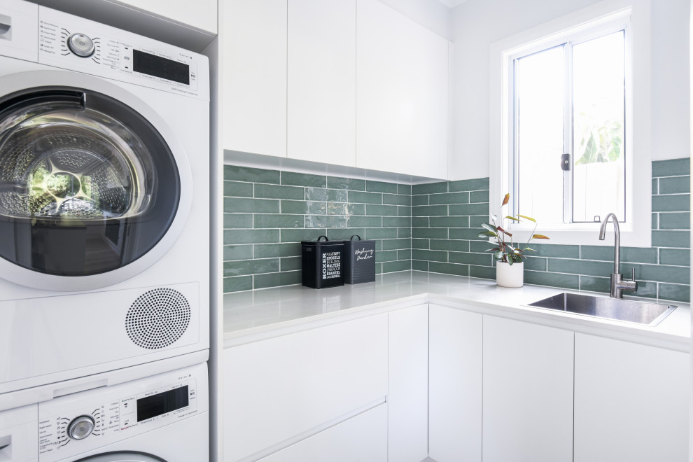 Inspiration för moderna u-formade tvättstugor enbart för tvätt, med grönt stänkskydd, vita väggar och en tvättpelare