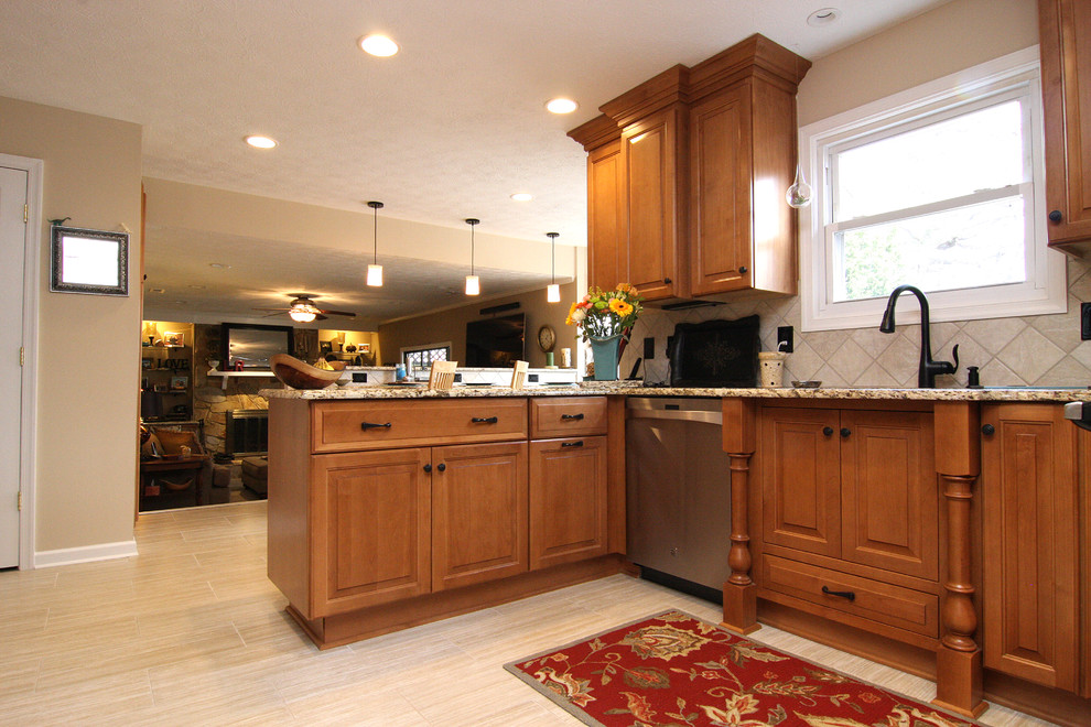 Large transitional u-shaped porcelain tile eat-in kitchen photo with an undermount sink, raised-panel cabinets, medium tone wood cabinets, granite countertops, beige backsplash, porcelain backsplash and stainless steel appliances