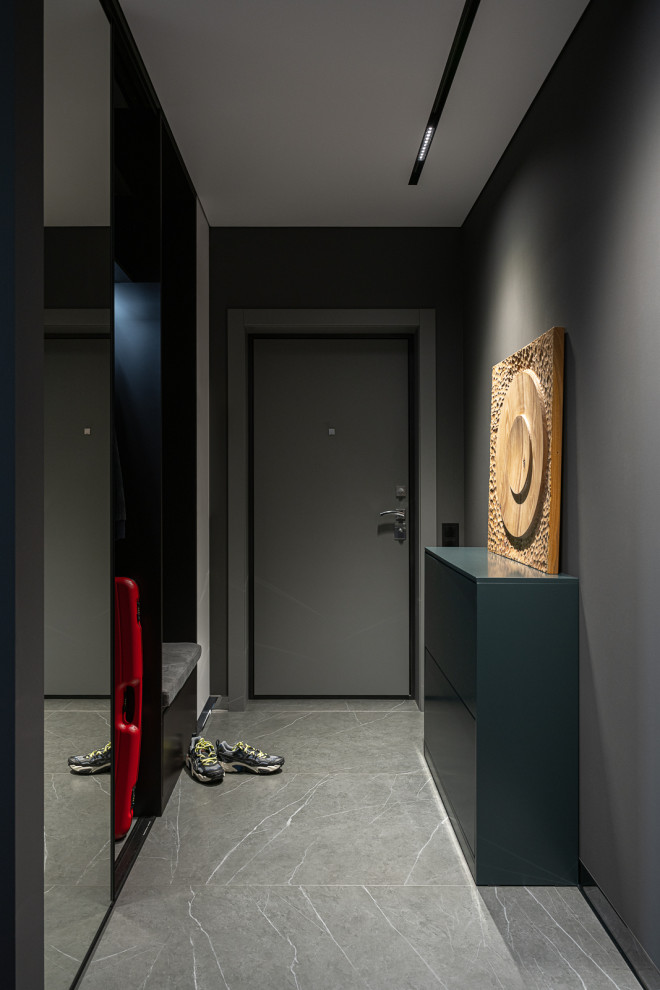На фото: узкая прихожая: освещение в современном стиле с серыми стенами, полом из керамогранита, серой входной дверью и серым полом с