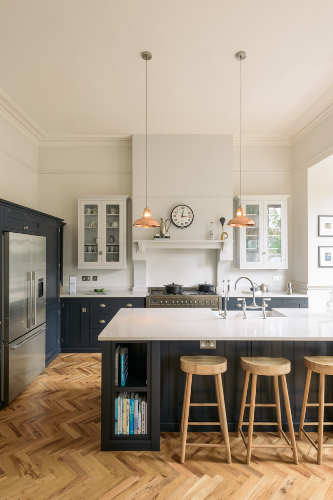Design ideas for a large transitional l-shaped eat-in kitchen in Other with a farmhouse sink, shaker cabinets, blue cabinets, solid surface benchtops, white splashback, stainless steel appliances, medium hardwood floors, with island and brown floor.