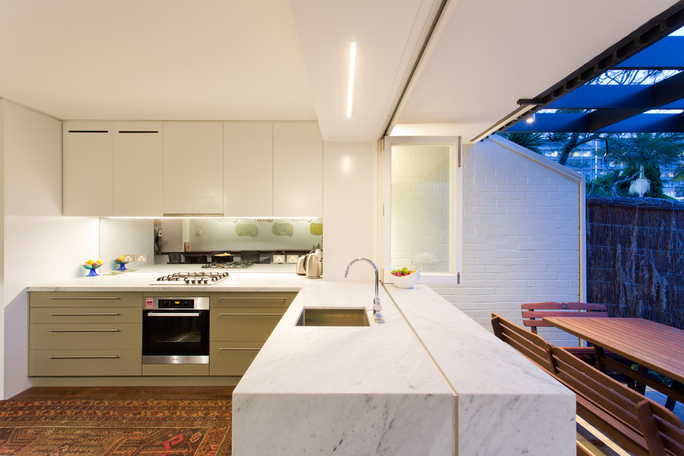 This is an example of a contemporary eat-in kitchen in Sydney with an undermount sink, flat-panel cabinets, green cabinets and stainless steel appliances.
