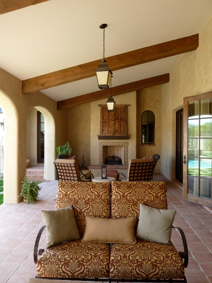 This is an example of a mid-sized mediterranean courtyard patio in Phoenix with a fire feature, tile and a roof extension.