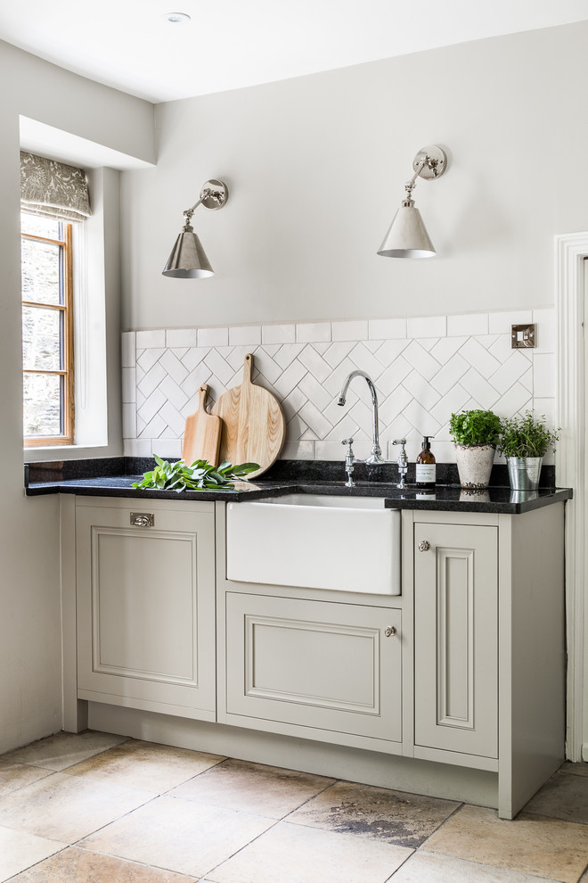 This is an example of a large country l-shaped eat-in kitchen in Other with a farmhouse sink, beaded inset cabinets, grey cabinets, wood benchtops, white splashback, ceramic splashback, panelled appliances, limestone floors, no island and multi-coloured floor.