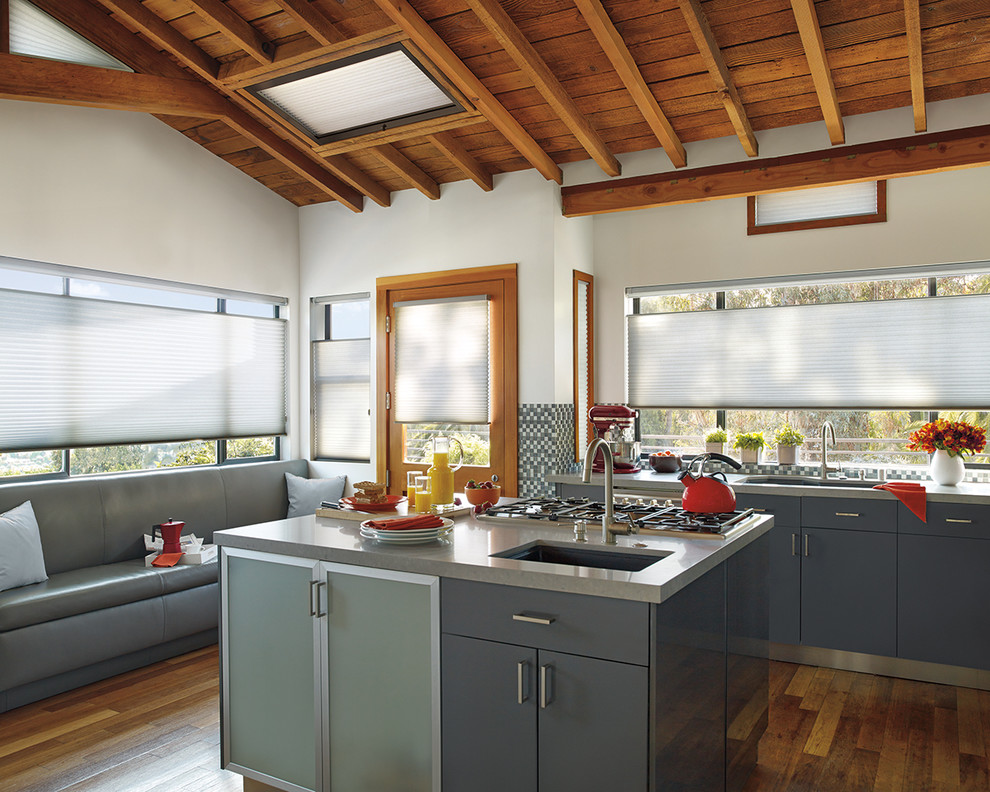 Mid-sized transitional l-shaped dark wood floor open concept kitchen photo with an undermount sink, flat-panel cabinets, gray cabinets, solid surface countertops, multicolored backsplash, mosaic tile backsplash, an island and stainless steel appliances
