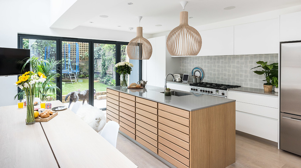 Inspiration for a scandinavian galley eat-in kitchen in London with an undermount sink, flat-panel cabinets, white cabinets, grey splashback, stainless steel appliances, medium hardwood floors and with island.