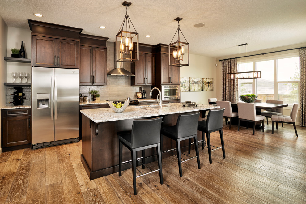 Open concept kitchen - transitional galley open concept kitchen idea in Calgary with recessed-panel cabinets, dark wood cabinets, quartz countertops, beige backsplash, stone tile backsplash and an island