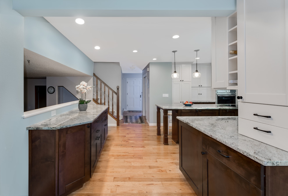 Eat-in kitchen - mid-sized transitional galley medium tone wood floor and brown floor eat-in kitchen idea in Denver with an undermount sink, shaker cabinets, white cabinets, granite countertops, blue backsplash, glass tile backsplash, stainless steel appliances, an island and beige countertops