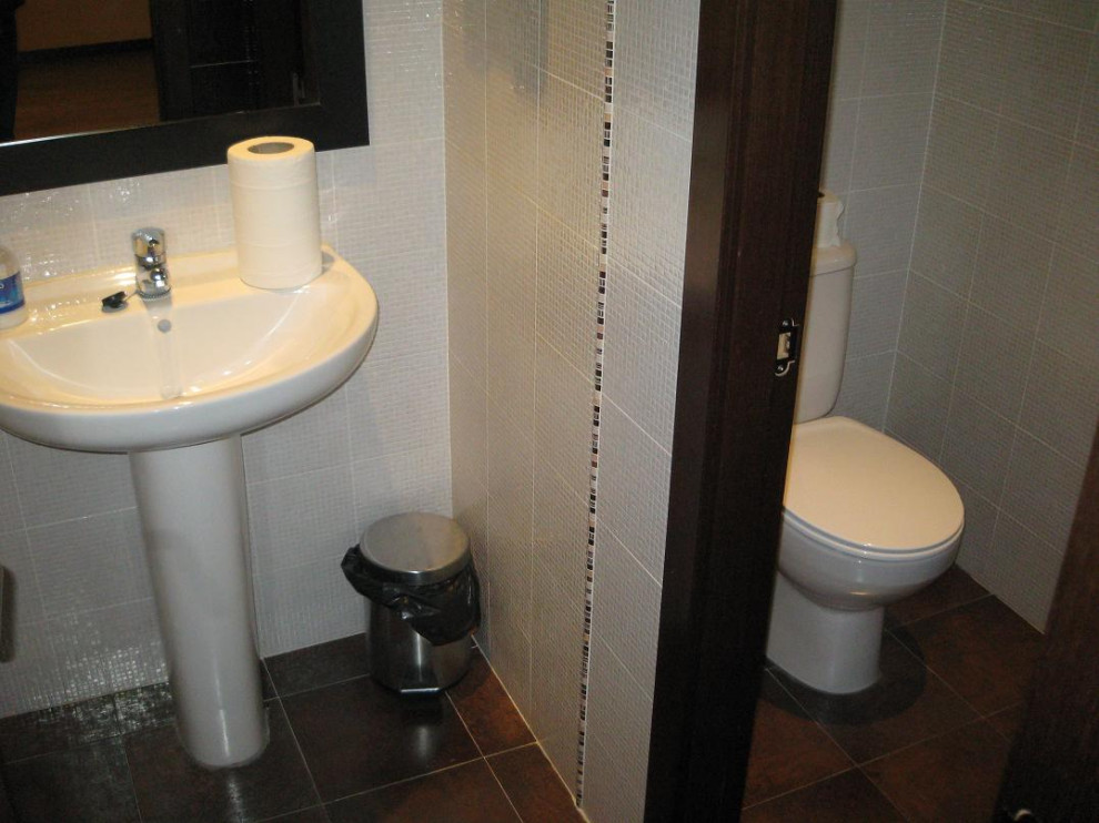 Photo of a mid-sized contemporary powder room in Madrid with white cabinets, a two-piece toilet, multi-coloured tile, ceramic tile, multi-coloured walls, a pedestal sink, brown floor, a freestanding vanity and recessed.
