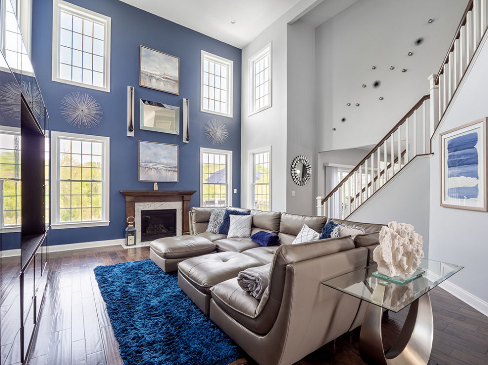 Immagine di un grande soggiorno design chiuso con pareti blu, parquet scuro, camino classico, cornice del camino in legno, TV a parete e pavimento marrone