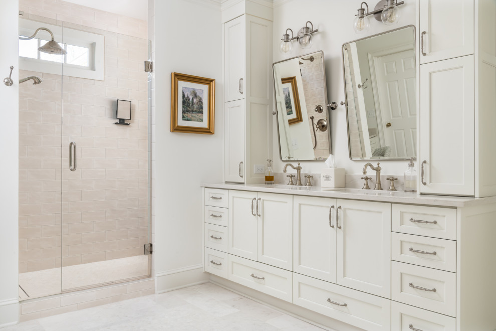 This is an example of a large classic ensuite bathroom in Atlanta with shaker cabinets, white cabinets, a freestanding bath, a walk-in shower, a two-piece toilet, white tiles, ceramic tiles, white walls, ceramic flooring, a submerged sink, engineered stone worktops, white floors, a hinged door, white worktops, an enclosed toilet, double sinks and a built in vanity unit.