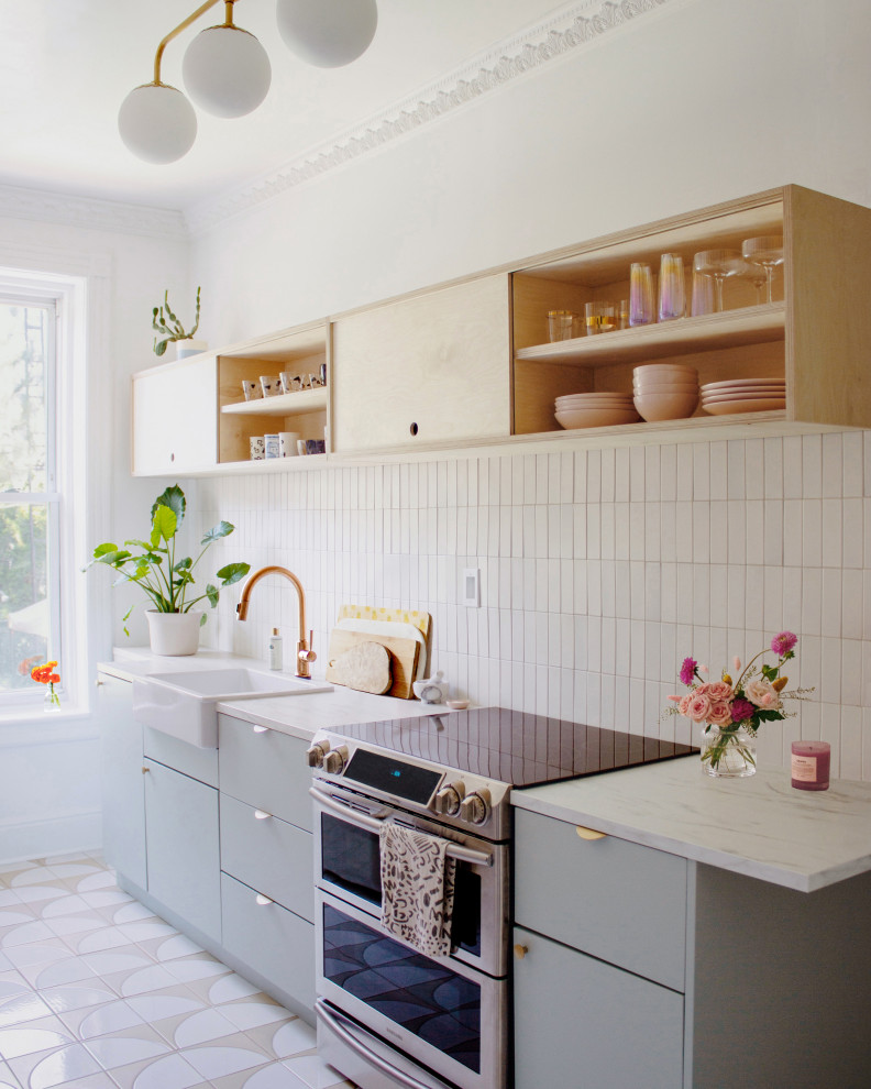 Inspiration for a small scandinavian galley separate kitchen in New York with a farmhouse sink, blue cabinets, beige splashback, ceramic splashback, stainless steel appliances, ceramic floors, no island, beige floor and white benchtop.