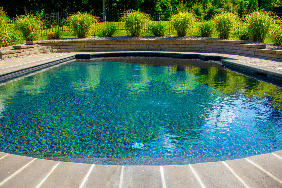 Photo of a mid-sized country side yard custom-shaped natural pool in Boston with natural stone pavers.