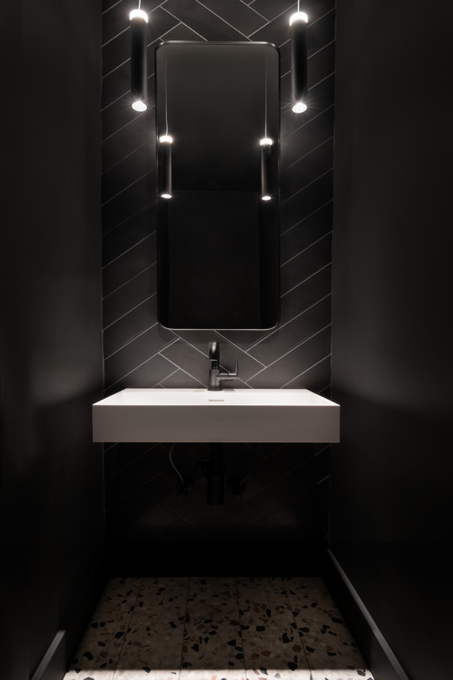 Foto di un piccolo bagno di servizio con piastrelle nere, piastrelle in pietra, pareti nere, pavimento alla veneziana, lavabo sospeso e top bianco