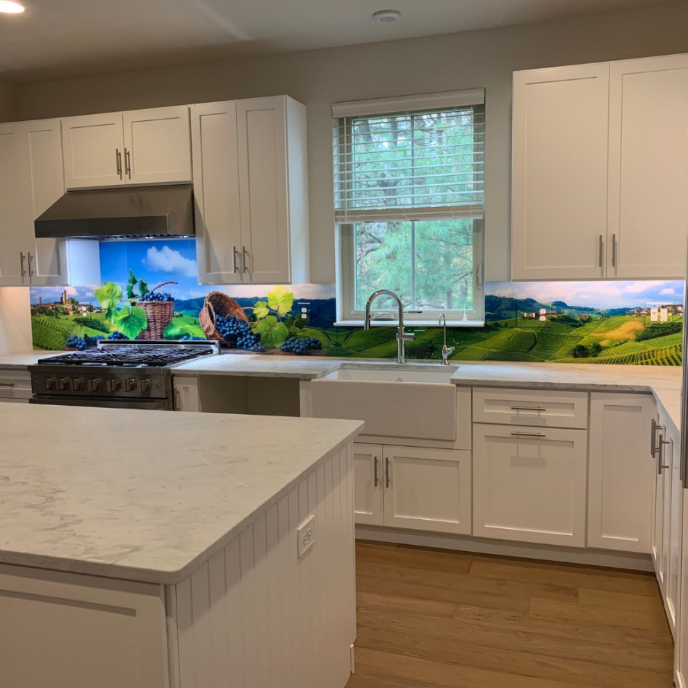 Mid-sized country l-shaped separate kitchen in Detroit with a farmhouse sink, shaker cabinets, white cabinets, multi-coloured splashback, glass sheet splashback, stainless steel appliances, with island and multi-coloured benchtop.