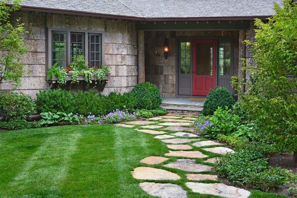 Photo of a mid-sized traditional front yard full sun garden in Other with natural stone pavers and a garden path.