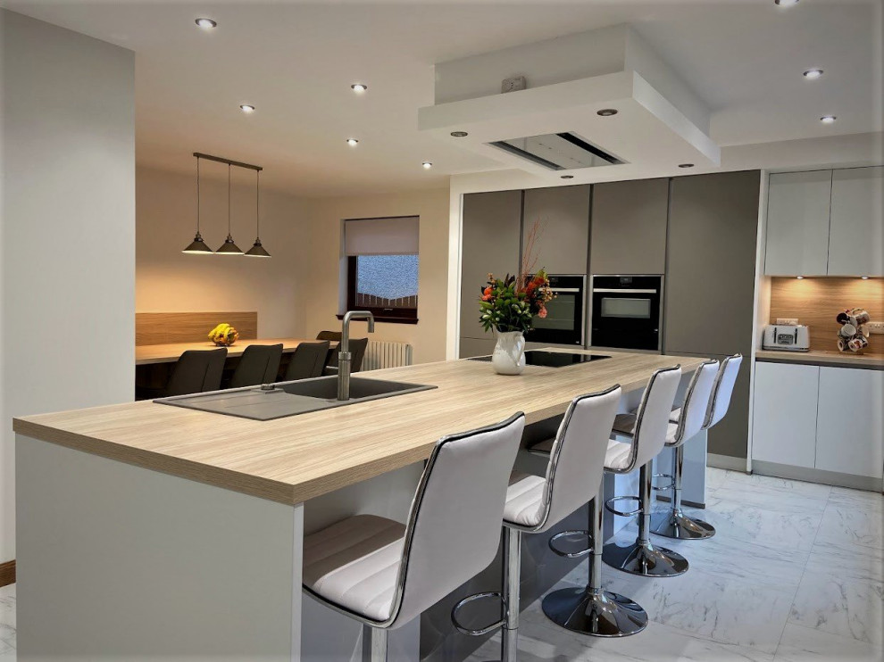 Photo of a contemporary eat-in kitchen in Other with a single-bowl sink, flat-panel cabinets, white cabinets, wood benchtops, brown splashback, black appliances, with island, white floor and brown benchtop.