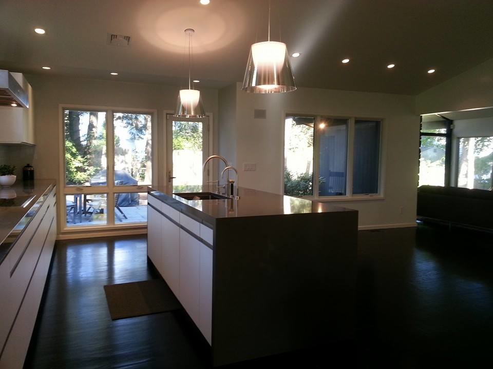 Example of a mid-sized transitional single-wall medium tone wood floor open concept kitchen design in Boston with a drop-in sink, flat-panel cabinets, white cabinets, granite countertops, white backsplash, stone tile backsplash, stainless steel appliances and an island