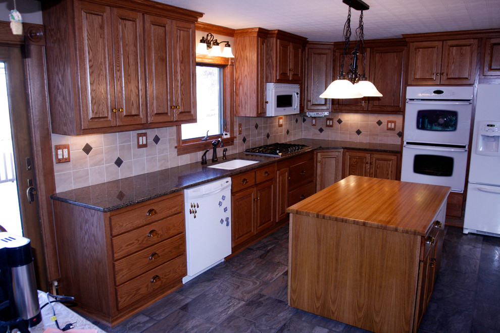 Example of a mid-sized l-shaped eat-in kitchen design with an undermount sink, raised-panel cabinets, medium tone wood cabinets, quartz countertops, beige backsplash, stone tile backsplash, white appliances and an island