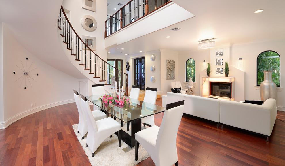 Large contemporary open plan dining in Miami with white walls, dark hardwood floors and a standard fireplace.