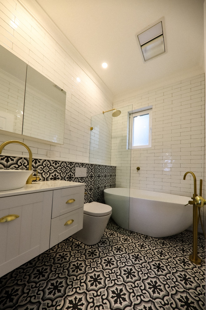 Photo of a small bohemian ensuite bathroom in Sydney with beaded cabinets, white cabinets, a freestanding bath, a walk-in shower, a one-piece toilet, white tiles, metro tiles, white walls, cement flooring, a vessel sink, engineered stone worktops, black floors, an open shower, white worktops, an enclosed toilet, a single sink, a floating vanity unit, a coffered ceiling and brick walls.