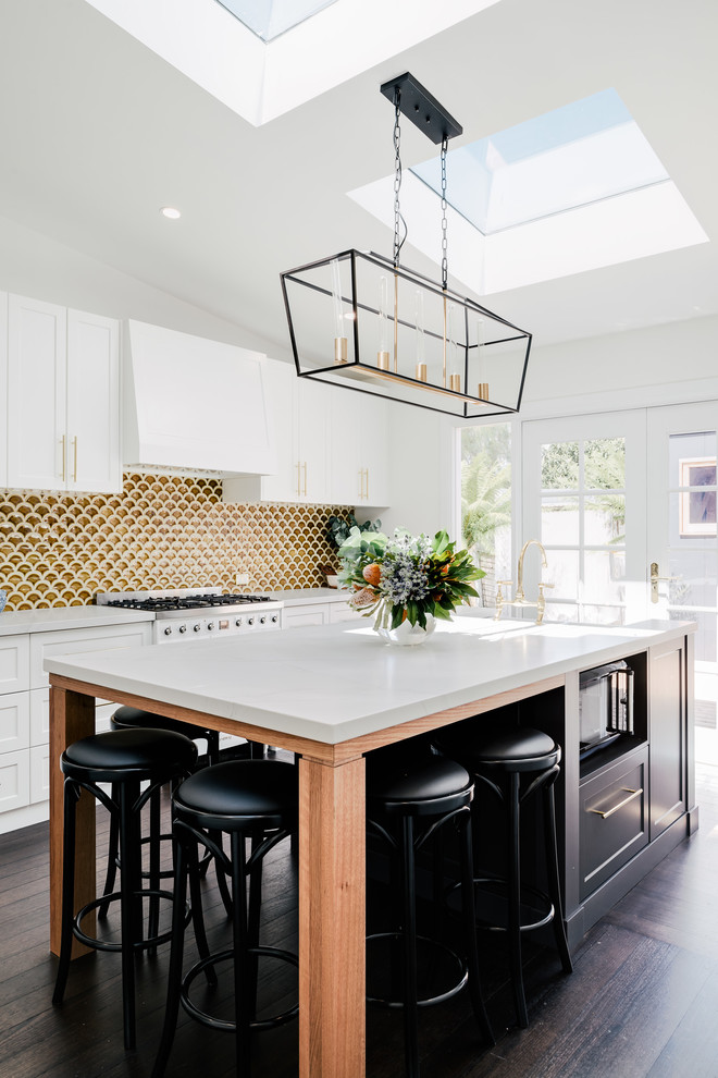 Large transitional galley eat-in kitchen in Hobart with a farmhouse sink, shaker cabinets, white cabinets, quartz benchtops, yellow splashback, ceramic splashback, stainless steel appliances, dark hardwood floors, with island, brown floor and white benchtop.