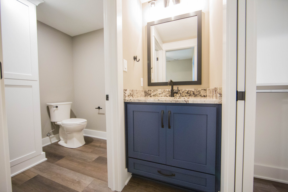 Idéer för ett mellanstort klassiskt flerfärgad toalett, med skåp i shakerstil, blå skåp, en toalettstol med separat cisternkåpa, bruna väggar, laminatgolv, ett undermonterad handfat, granitbänkskiva och brunt golv