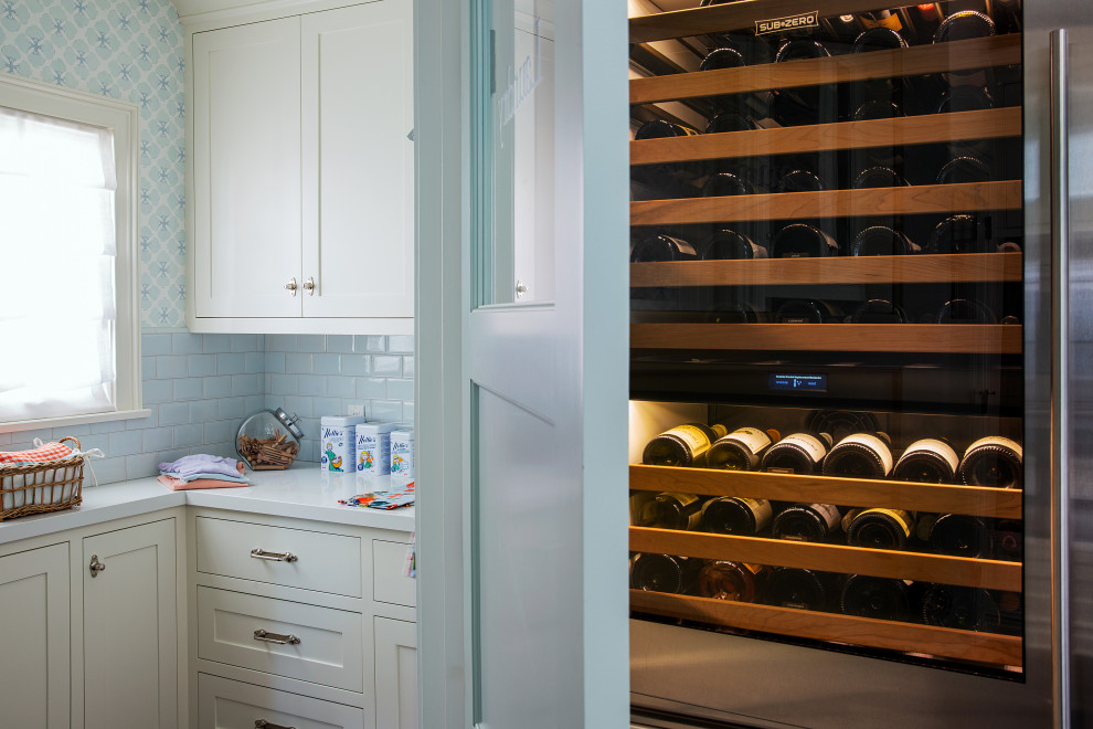 Example of a small classic wallpaper dedicated laundry room design in Los Angeles with an undermount sink, shaker cabinets, white cabinets, quartz countertops, blue backsplash, blue walls, a stacked washer/dryer and white countertops