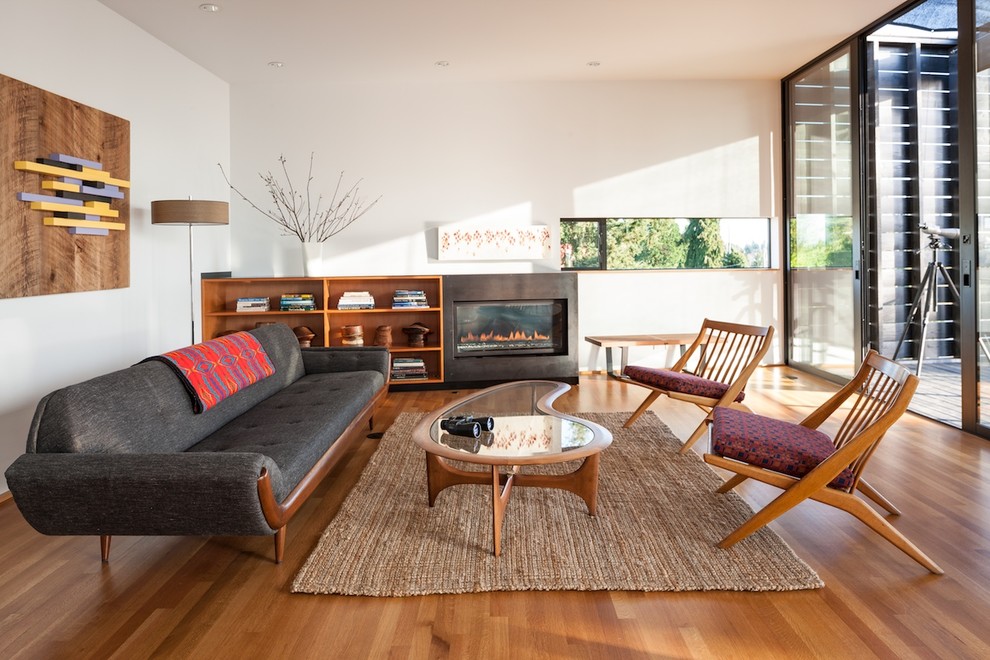 This is an example of a contemporary formal living room in Seattle with white walls, medium hardwood floors, a standard fireplace, a metal fireplace surround and no tv.
