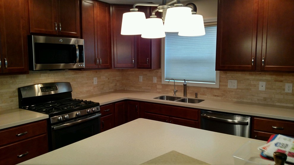 Mid-sized transitional l-shaped kitchen photo with a double-bowl sink, flat-panel cabinets, dark wood cabinets, quartz countertops, beige backsplash, stone tile backsplash, stainless steel appliances and an island