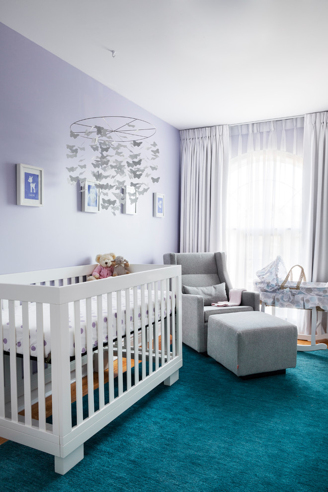 Photo of a transitional nursery for girls in Toronto with purple walls and medium hardwood floors.