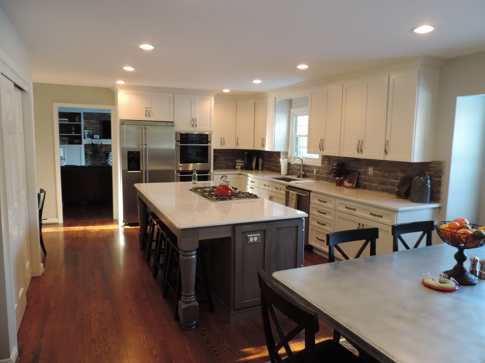 Large transitional l-shaped eat-in kitchen in Columbus with an undermount sink, shaker cabinets, grey cabinets, quartz benchtops, grey splashback, stone tile splashback, stainless steel appliances, medium hardwood floors and with island.
