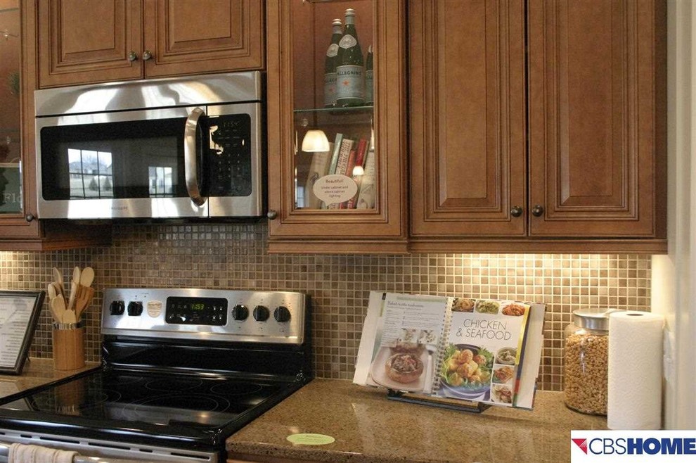 Example of a l-shaped kitchen design in Omaha with raised-panel cabinets, medium tone wood cabinets, granite countertops and an island